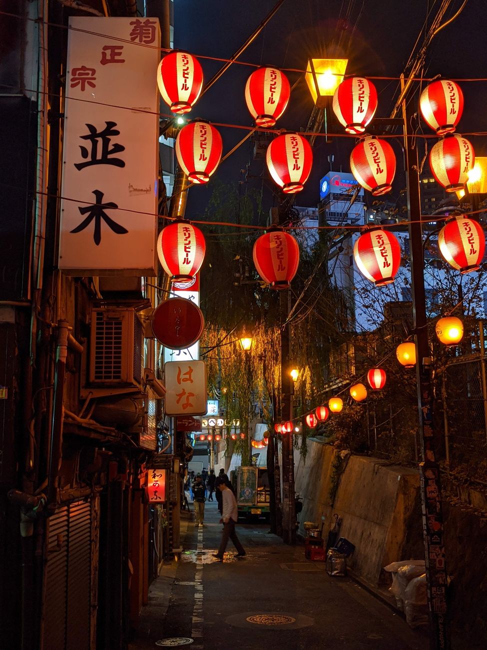 A paper lantern casting warm glow on wooden lattice screens in Gion